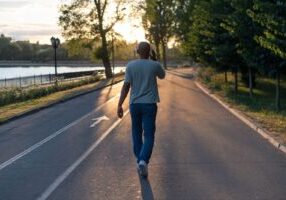 A person wearing headphones and walking on a street, symbolizing distracted walking. This image relates to pedestrian safety, emphasizing the risks associated with mobile device use while walking and the importance of staying alert in public spaces.