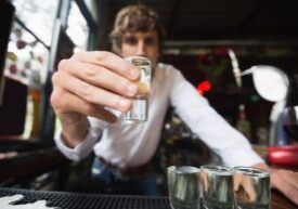 A bartender serving shots at a bar, symbolizing dram shop liability and social host responsibility in preventing drunk driving accidents.