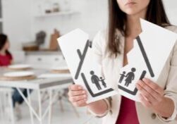 Close-up of a woman holding a torn family illustration, symbolizing the complexities of property division in Alabama divorces, with a child visible in the background.