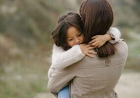 A parent holding children in their arms, conveying a sense of care and responsibility, with a focus on FAQs about stepparent adoptions in Alabama. The image represents the bond between stepparents and their children, offering insight into the legal process and requirements for stepparent adoption in Alabama.