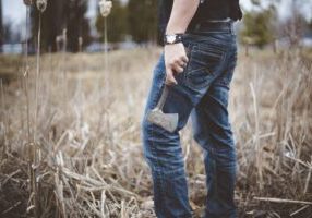 A person holding an axe while working on a farm, surrounded by wild crops, symbolizing the labor-intensive nature of agriculture. This image relates to farming and agricultural accidents, highlighting injury risks and the compensation options available for workers in such environments.