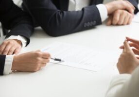 Lawyers and a client discussing a case at a table, symbolizing a formal meeting. This image relates to filing a complaint against an attorney for legal malpractice, highlighting the process of addressing professional misconduct or negligence.