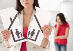 A woman holding a torn paper illustration of a family, symbolizing the division of marital property during divorce proceedings in Alabama.