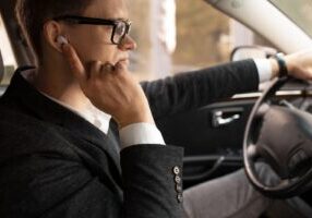 A man driving a car with his focus directed away from the road, illustrating the risks of inattention and cognitive distractions in the context of distracted driving.