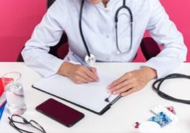 A doctor is writing notes on a clipboard, with a focused expression, symbolizing medical documentation. The image hints at the importance of accuracy in patient records, a key factor in preventing medical malpractice incidents.