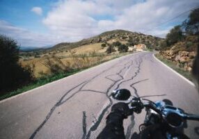 Close-up of a motorcycle in the front view, navigating a road with lane splitting. The image highlights the potential risks associated with this maneuver, such as accidents involving other vehicles or riders.