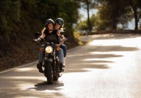 A motorcycle with two riders traveling on a scenic road, highlighting the potential for passenger injuries and the complexities of liability in motorcycle accidents.