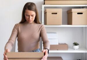 A woman carefully inspects a product in its box, looking for any defects. The image emphasizes the importance of product quality and safety, reflecting consumer diligence in identifying potential issues.