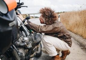 A person closely inspecting a motorcycle, emphasizing the process of assessing bike damage and pursuing compensation after a motorcycle accident.