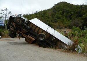 Side view of a crushed truck on the roadside, severely damaged and lying on its side after an accident.