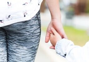 A close-up of a parent and child holding hands, symbolizing care and connection. This image relates to the best interest of the child in Alabama custody cases, highlighting the guiding principle in custody decisions.