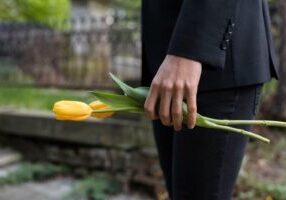 A person stands in a cemetery holding a flower, symbolizing mourning. The image reflects the somber reality of wrongful death claims, underscoring the legal pursuit of justice for a loved one's untimely passing due to negligence.